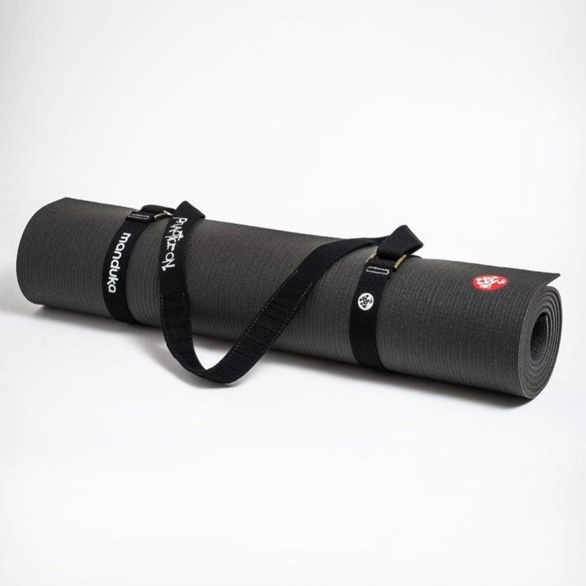 black yoga mat carrier strap fastened around a rolled up black manduka yoga mat