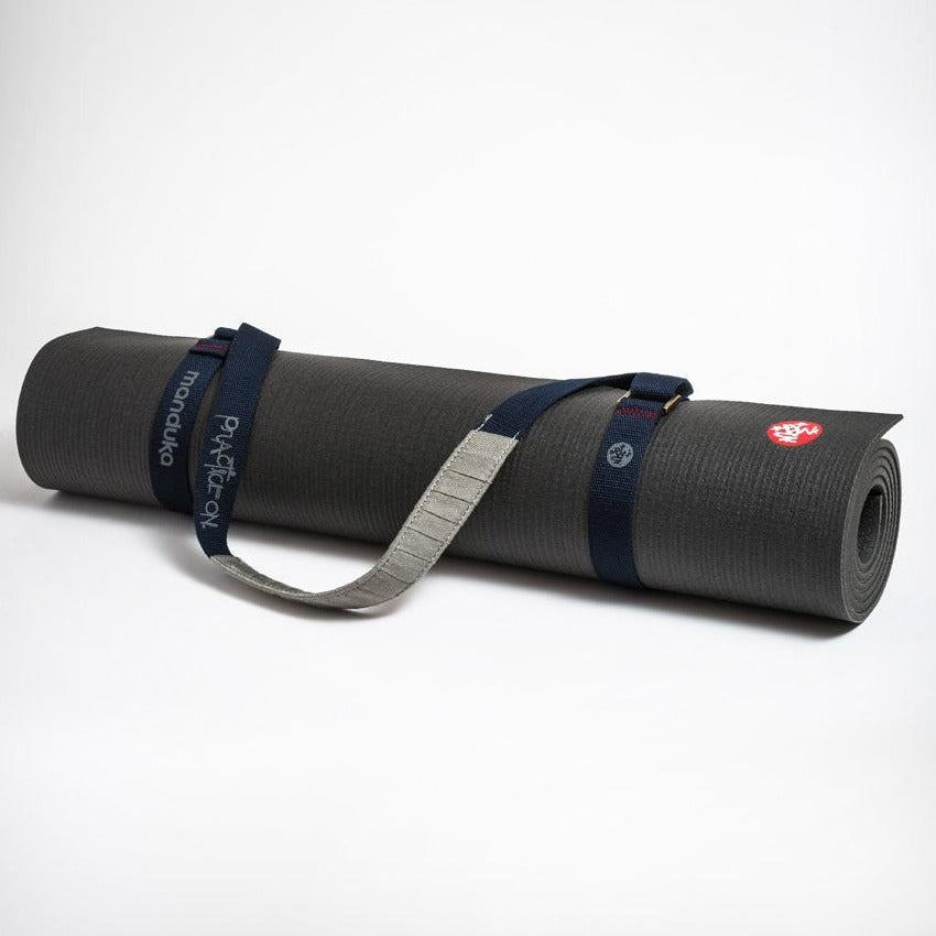 dark blue yoga mat strap fastened around a rolled up black manduka yoga mat