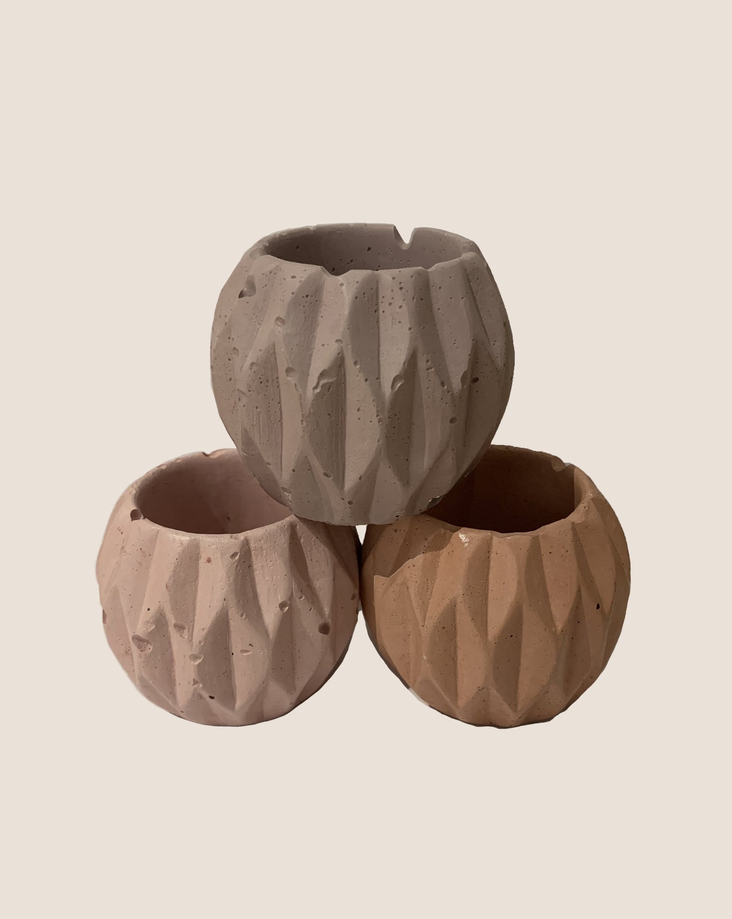 trio of mini handmade planters stacked in a pyramid in various colors