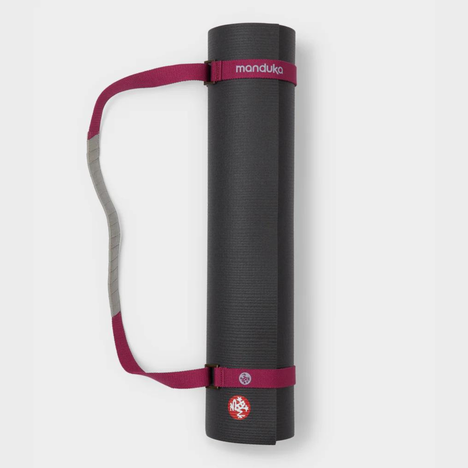 manduka mat rolled up being held by rose color mat carrier strap