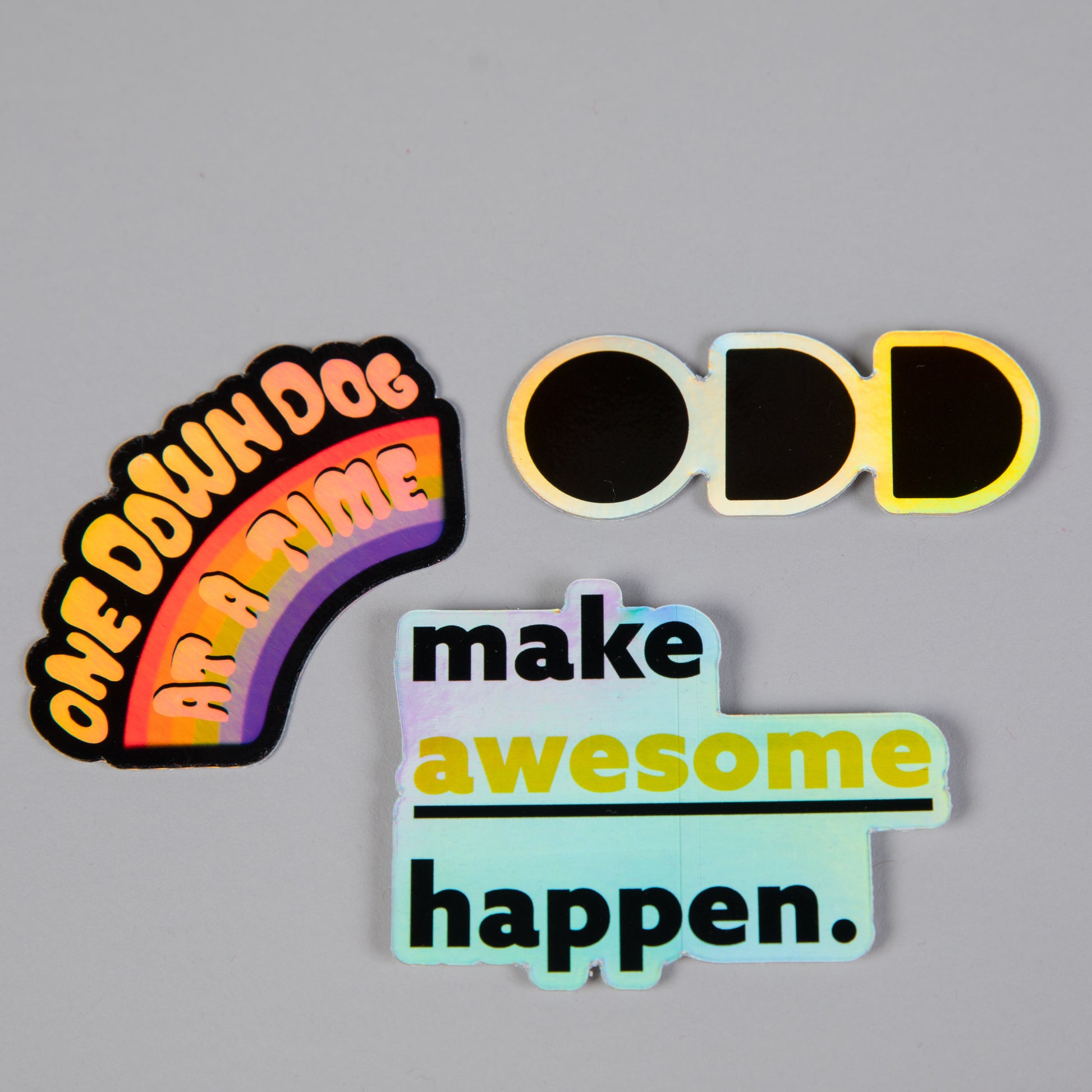 three holographic stickers saying "One down dog at a time" "ODD" and "Make Awesome Happen"