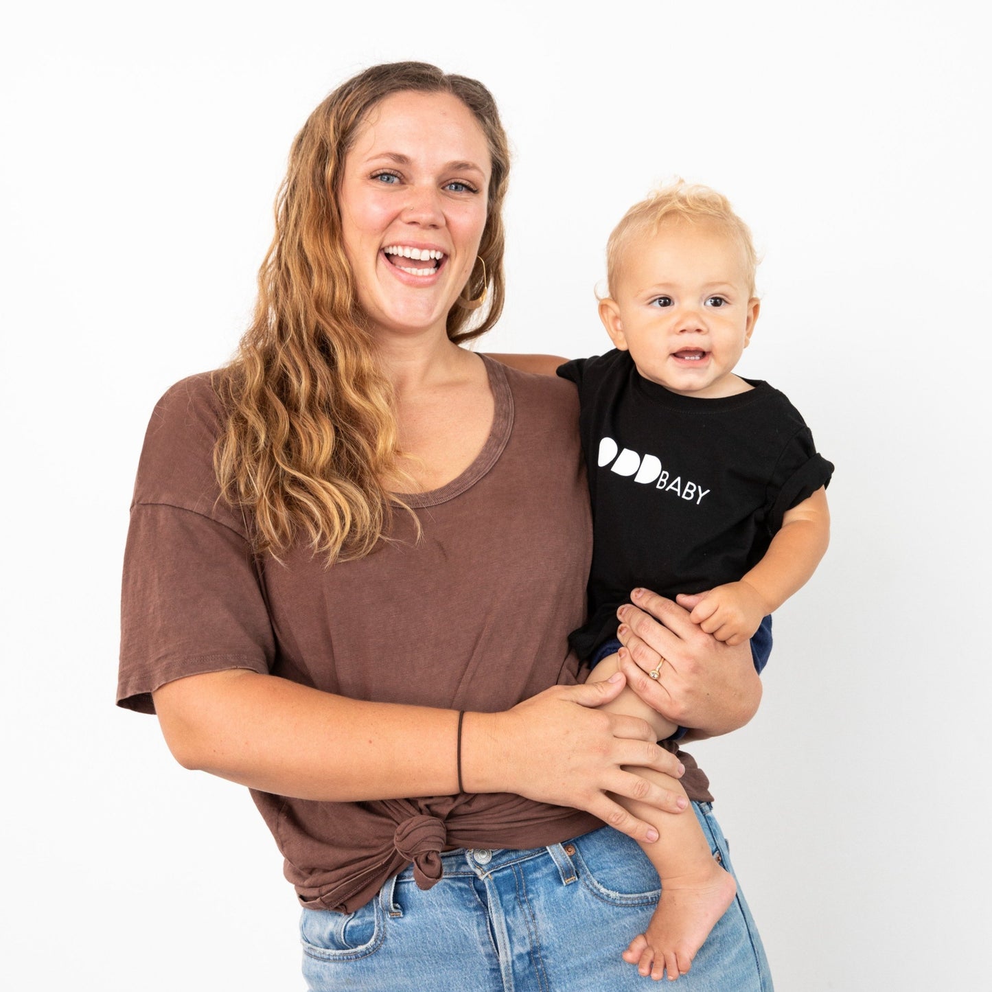 Woman holding baby in black tee with ODD baby written in white letters