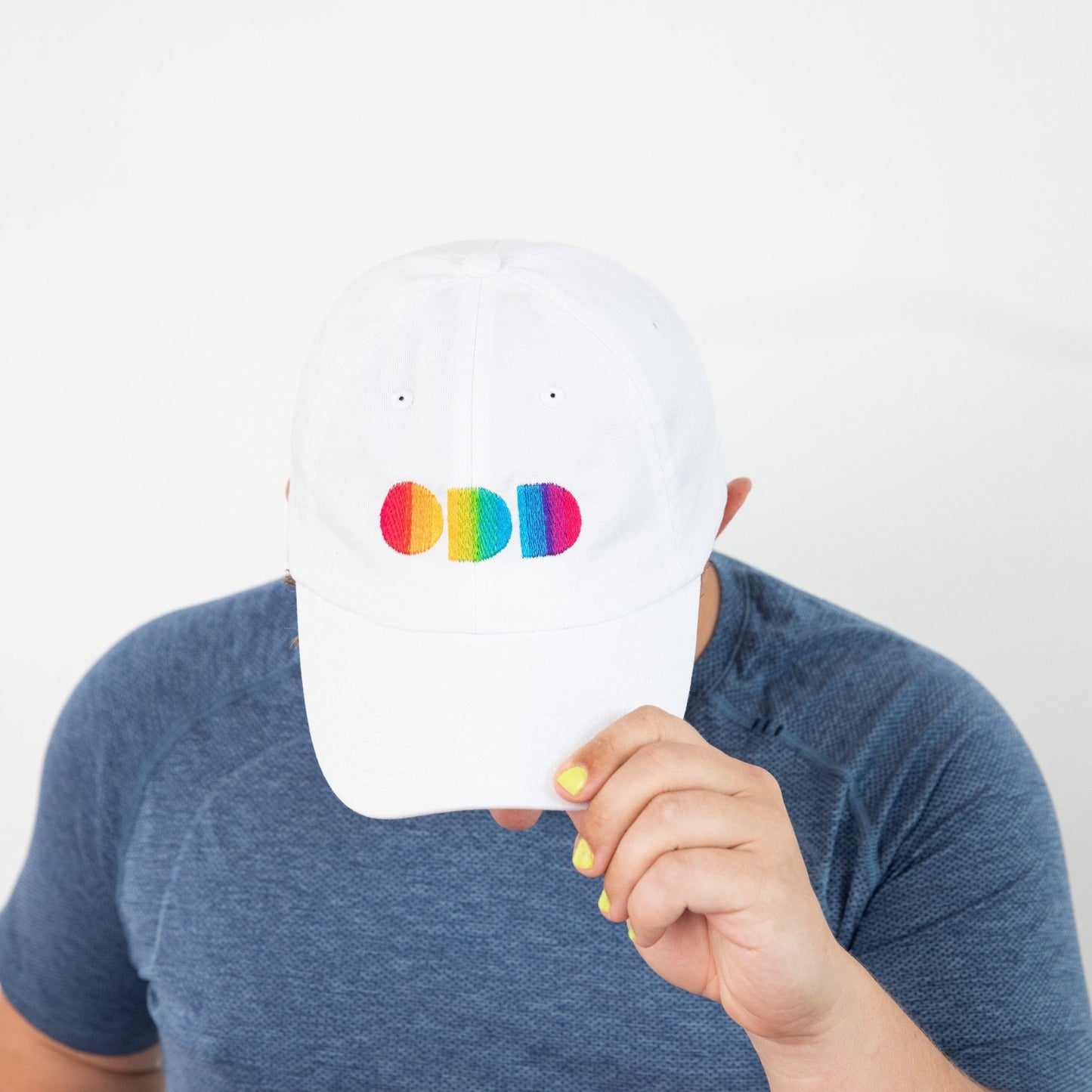Top view of white baseball cap with rainbow colored embroidered letters ODD