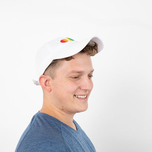 side view of person wearing white baseball cap with rainbow embroidered letters ODD