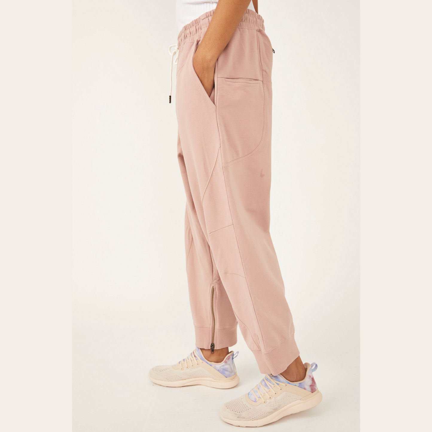 side view of light pink sweat pants with hands in pocket and zipper on the inside of the ankle 