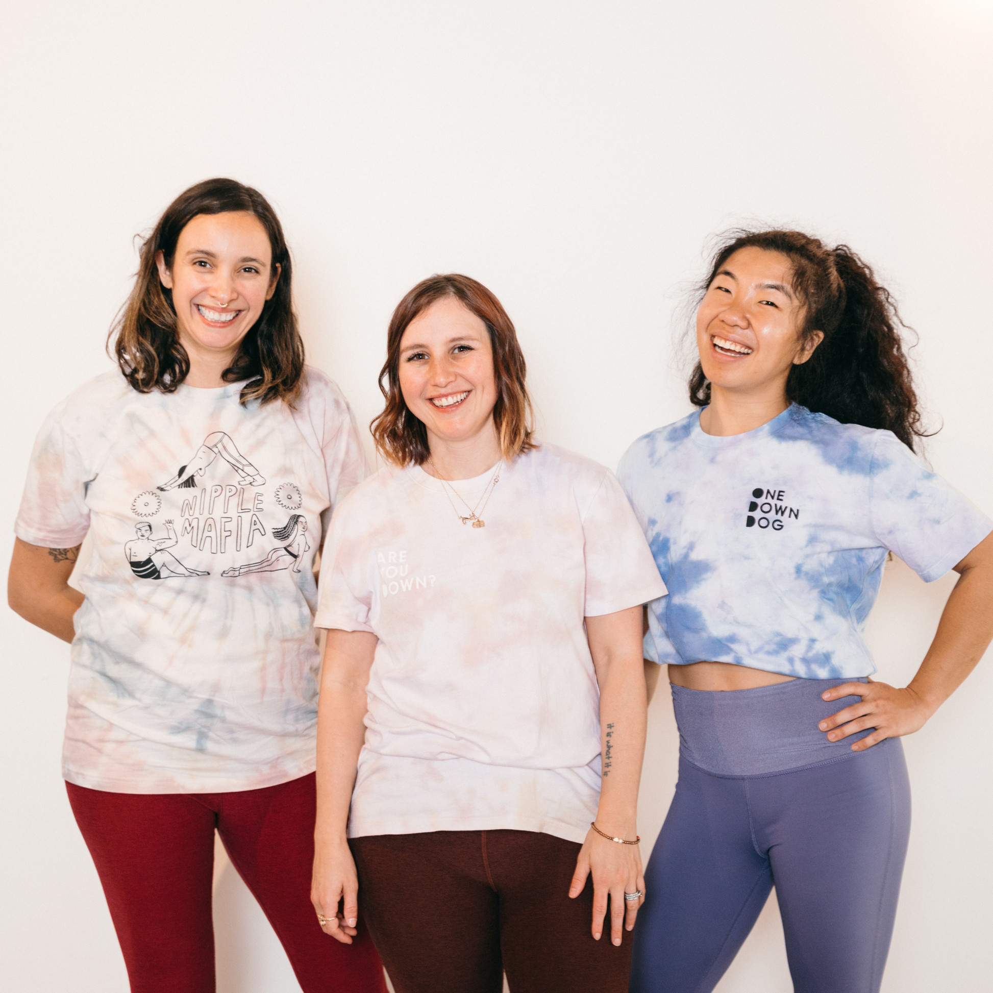 Trio wearing tie-dye tees with different logos and phrases