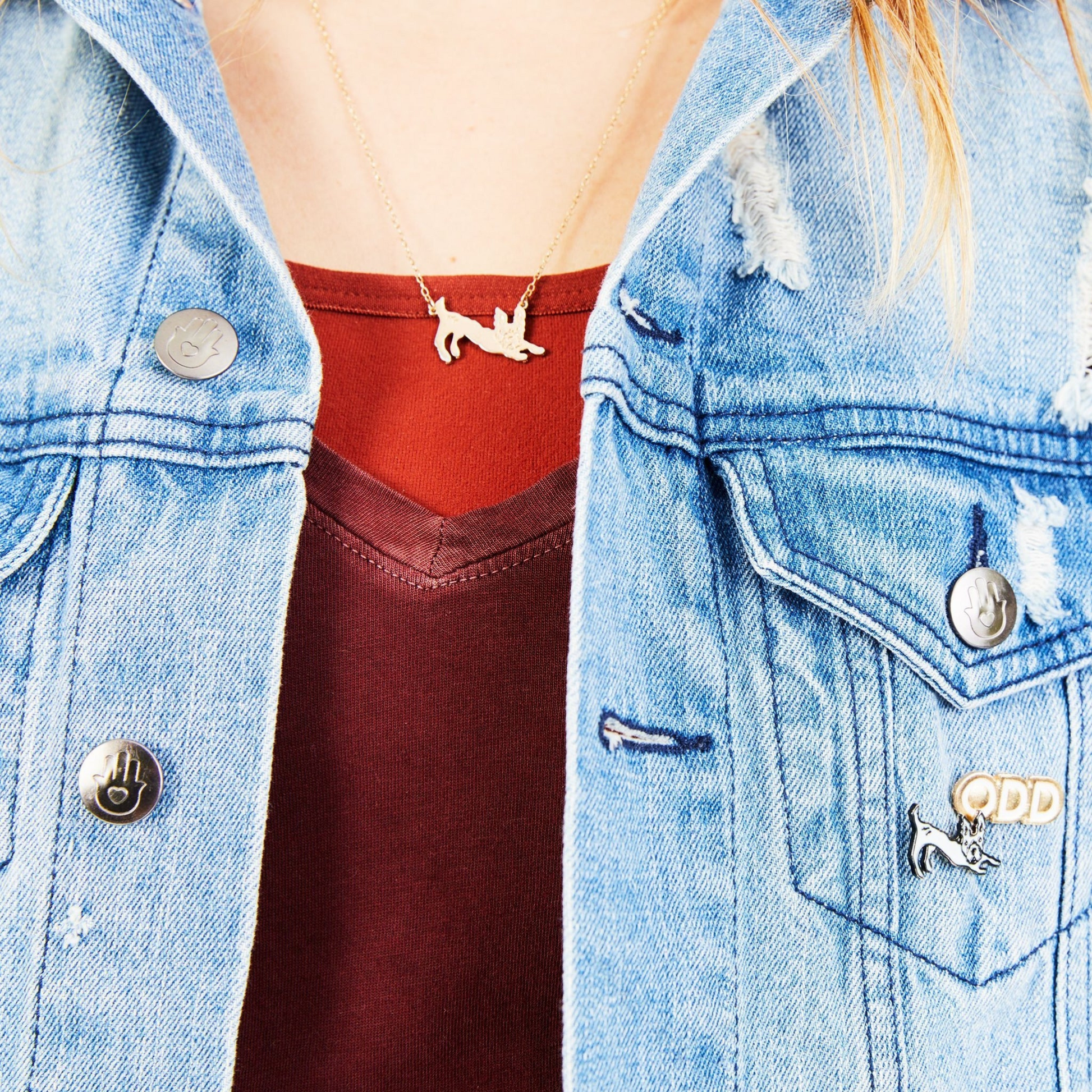 person wearing jean jacket and red top with gold dog necklace